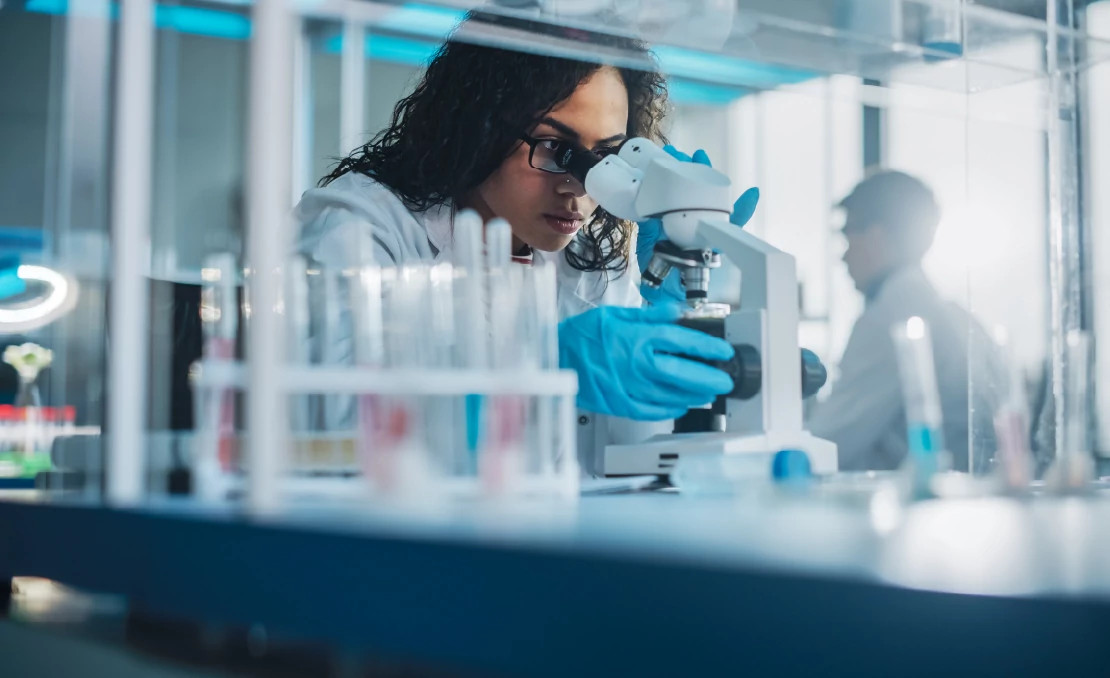 woman looking through microscope in a lab