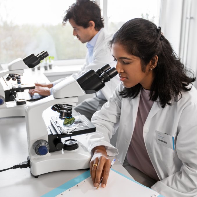 lab worker looking through microscope