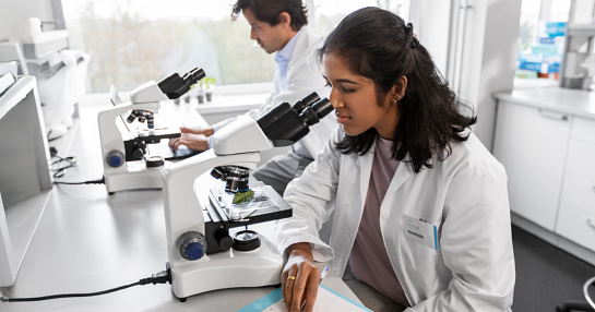 lab worker looking through microscope